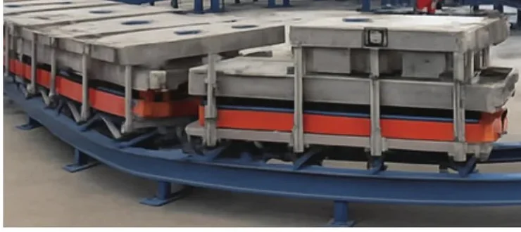 Close-up of ground-rail carrier fixtures with heated platens (orange bands) holding refrigerator-door moulds