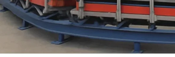 Close-up of the heavy-duty closed-loop steel rail on the bend with carrier underframe and wheels